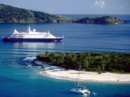 The small intimate size of the Seadream megayachts is captured with a catamaran in the foreground near Jost van Dyke © SW